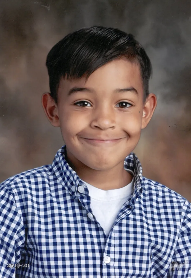 School portrait of one of the boys in a checked shirt, grinning