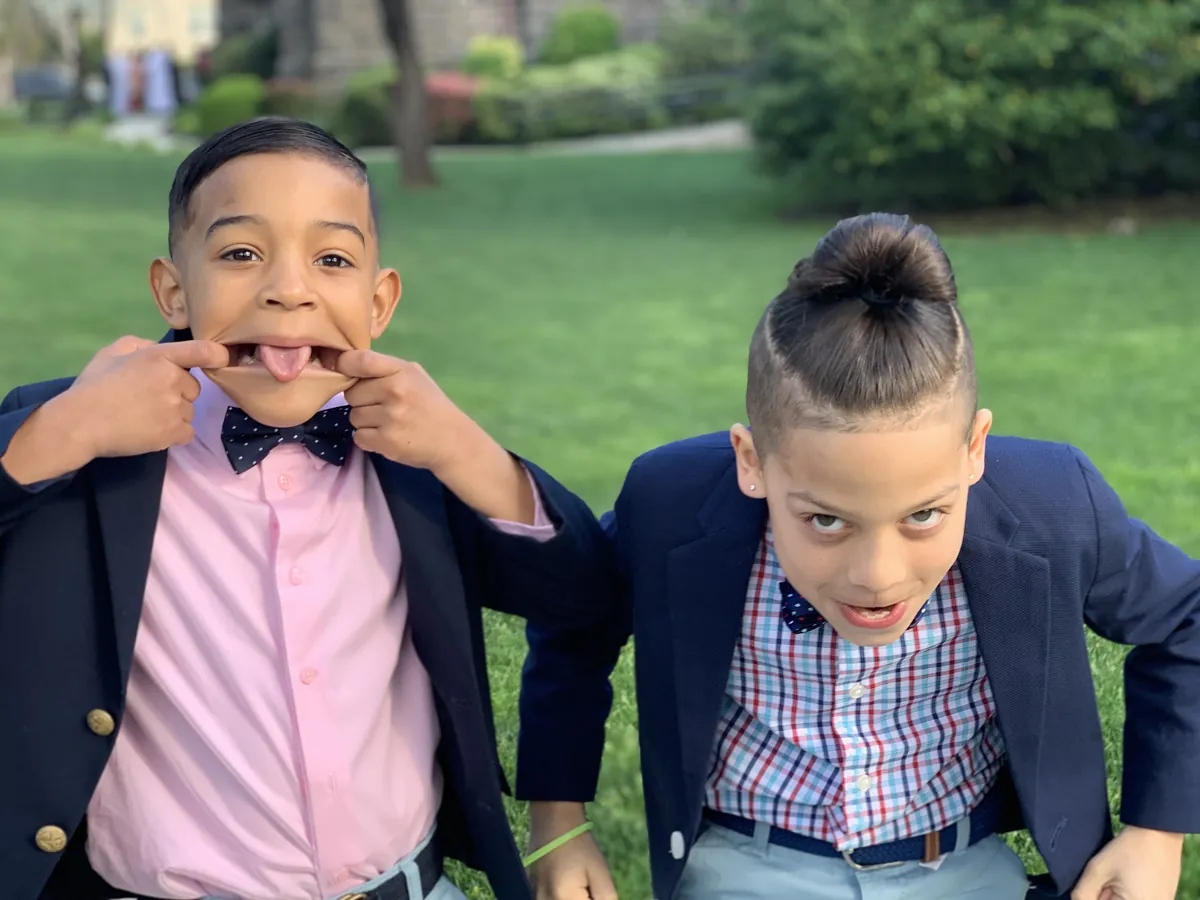 The boys in blazers making silly faces in a park